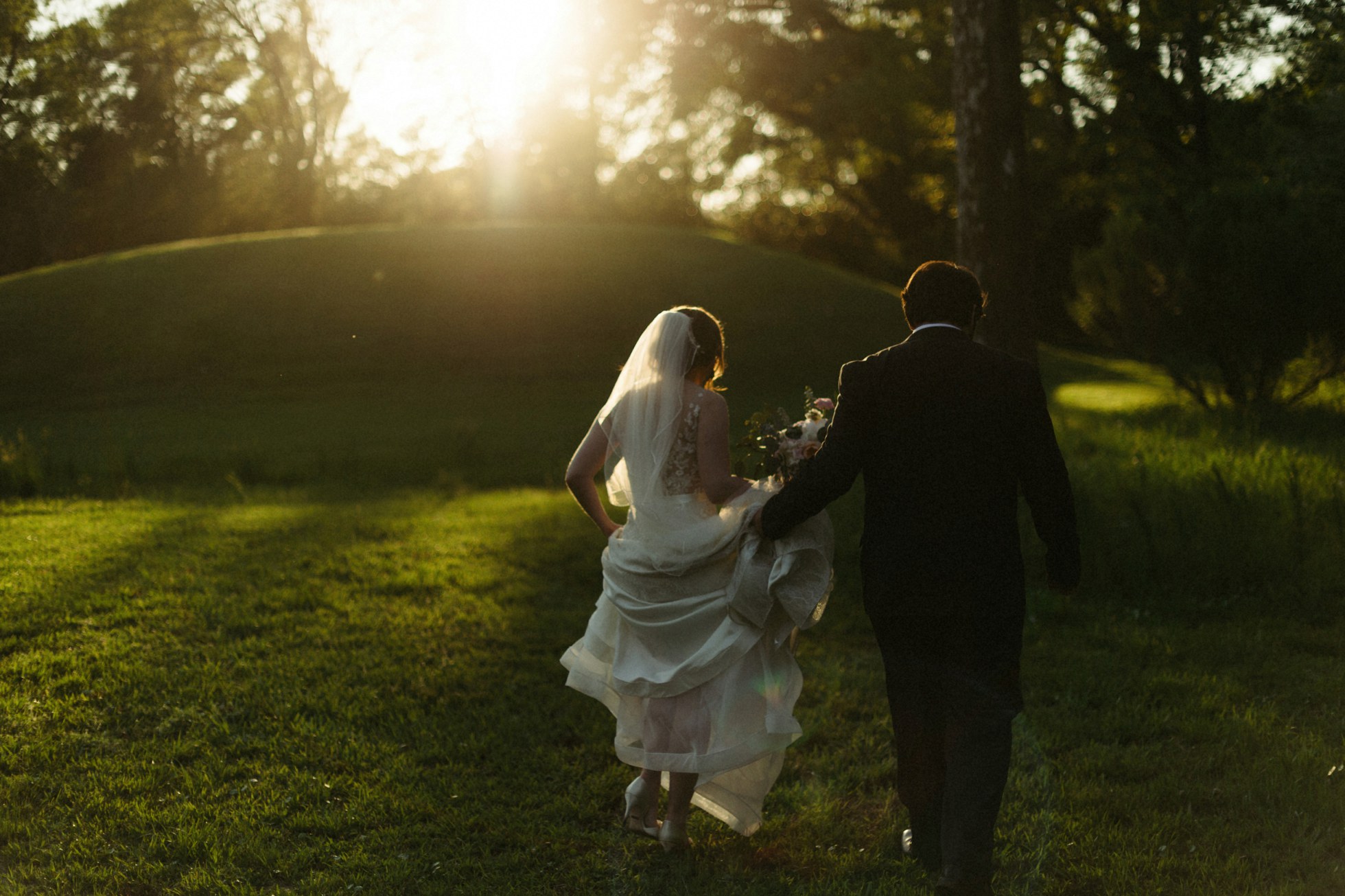 bride and groom walking into sunset